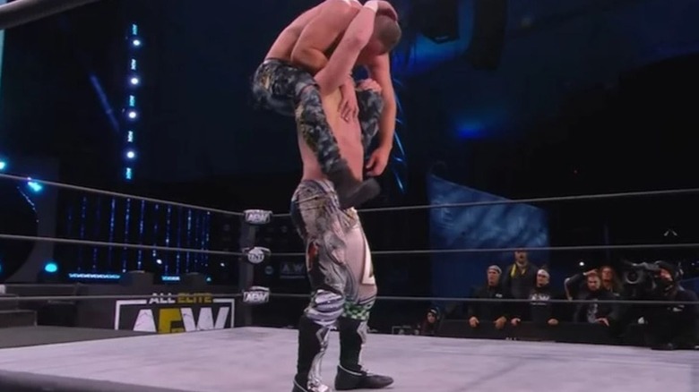 Kenny Omega gets Jon Moxley up on his shoulders for a One-Winged Angel