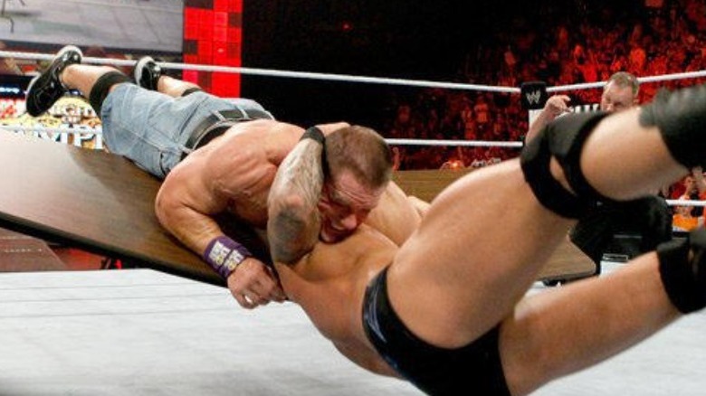 Randy Orton putting John Cena through table