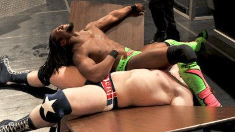 Kofi Kingston and Sheamus laying on a broken table