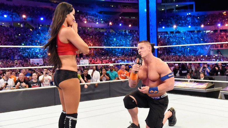 John Cena proses to Nikki Bella in the middle of the ring after their WrestleMania victory.