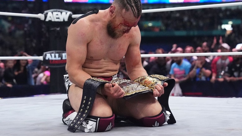 Bryan Danielson kneeling and staring at title belt