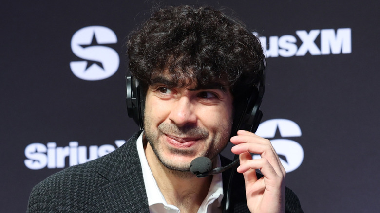 Tony Khan smiling and touching a headset that he's wearing