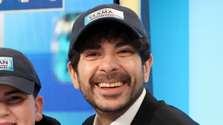 Tony Khan smiles while wearing a hat