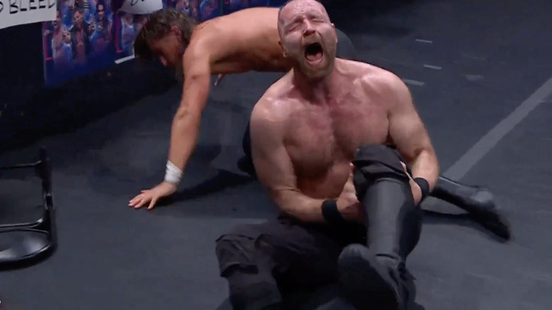 Jon Moxley howls in pain and clutches his knee