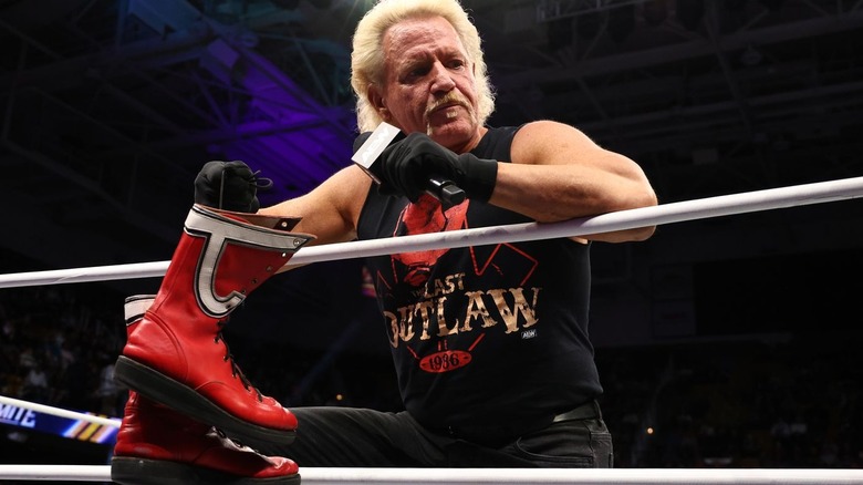 Jeff Jarrett holds his boots in one hand and a microphone in the other as he leans on the ropes on "AEW Dynamite."