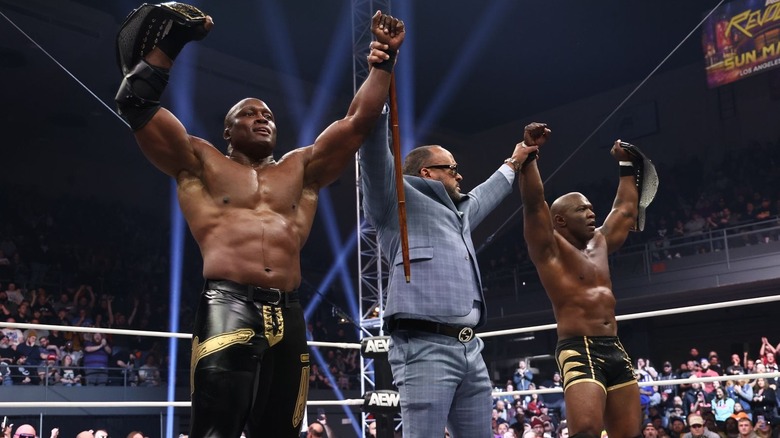 MVP raises the arms of Bobby Lashley and Shelton Benjamin as they raise their AEW tag title belts