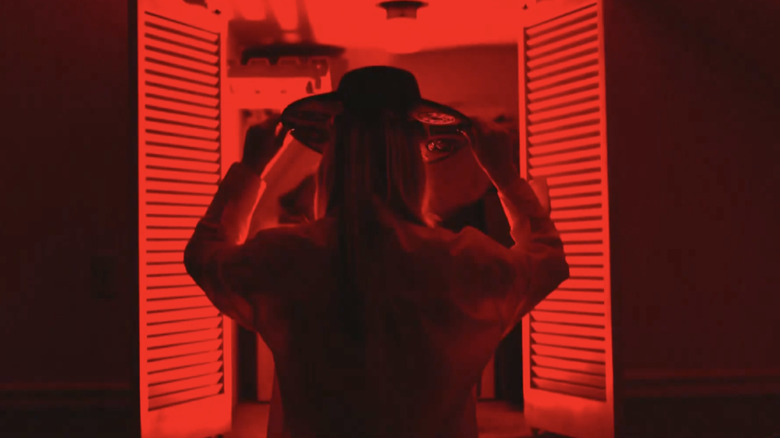 Julia Hart putting on her hat while standing in front of red closet doors in a vignette that aired on "AEW Dynamite."