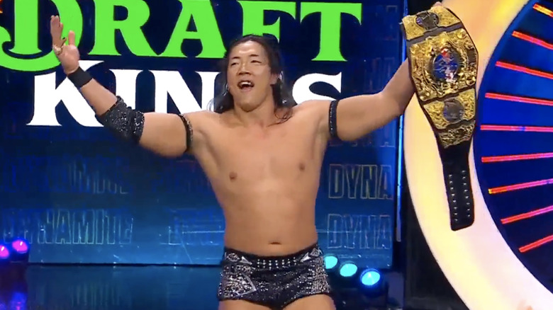 Konosuke Takeshita raising his title belt and posing on the stage during "AEW Dynamite."