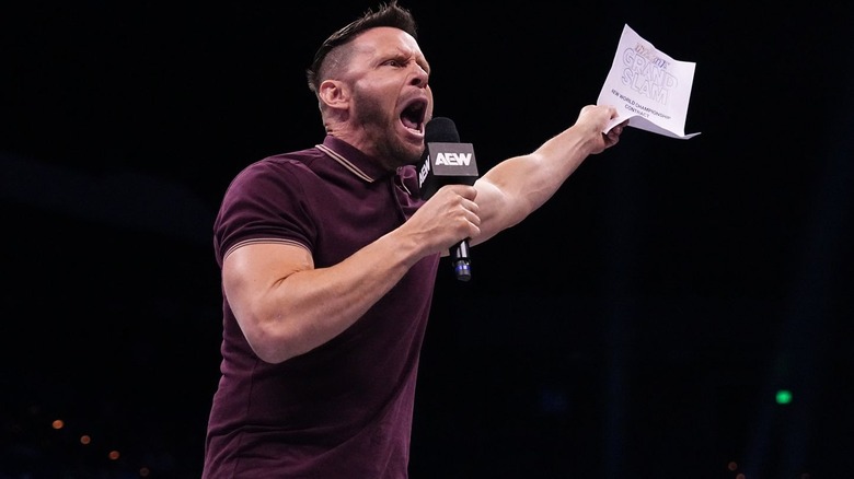 Nigel McGuinness screams into microphone while holding up contract