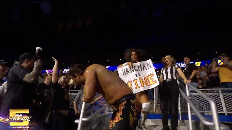 Robinson holding up a fan sign as he brawls through the crowd with Page