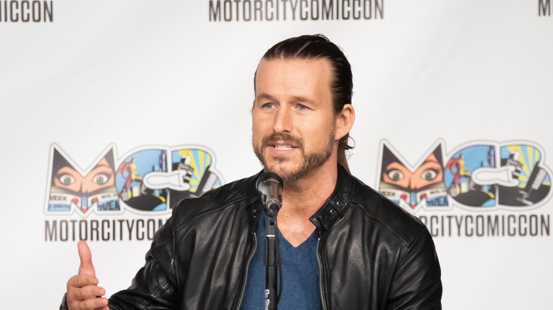 Adam Cole answers a question at a press conference 