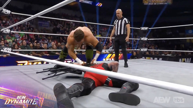 MJF placing Rhodes' arm through a chair