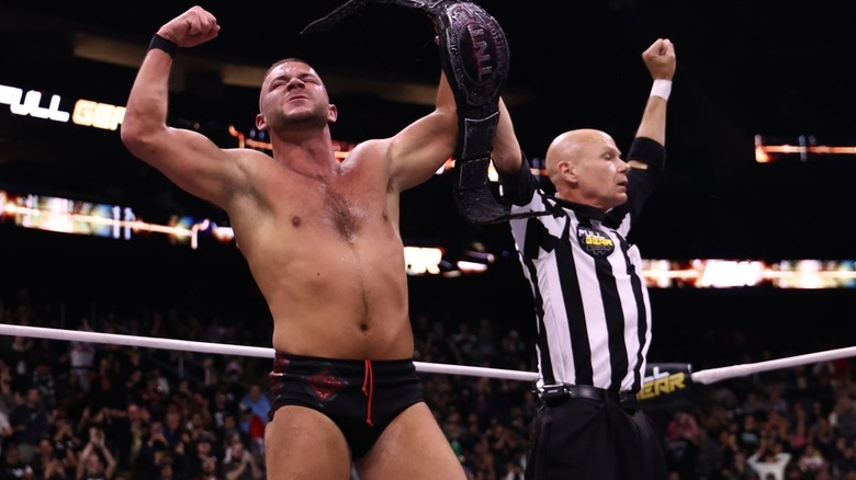 Daniel Garcia celebrates with the TNT title while the ref raises his arm at AEW Full Gear.