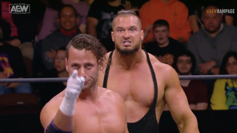 Wardlow standing behind an unsuspecting Taven