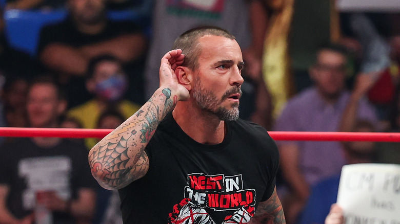 CM Punk cupping his right ear with his right hand