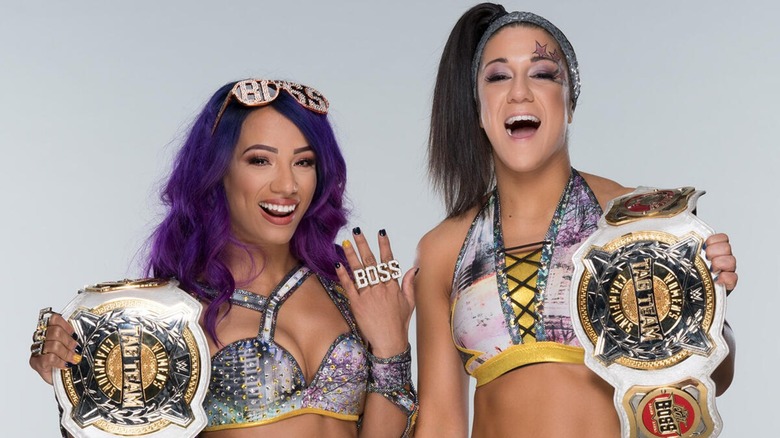 Sasha Banks (Mercedes Mone) y Bayley posando con los títulos de parejas femeninos de la WWE