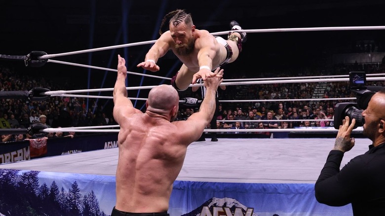 Bryan Danielson flies out of the ring to hit Jon Moxley