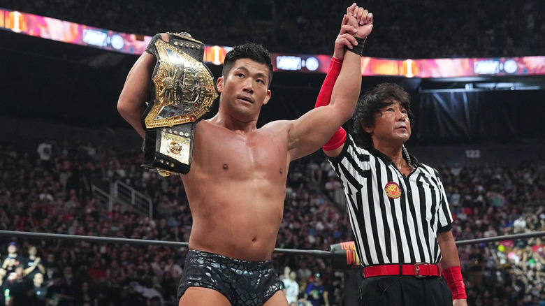 SANADA holds his title belt up in victory