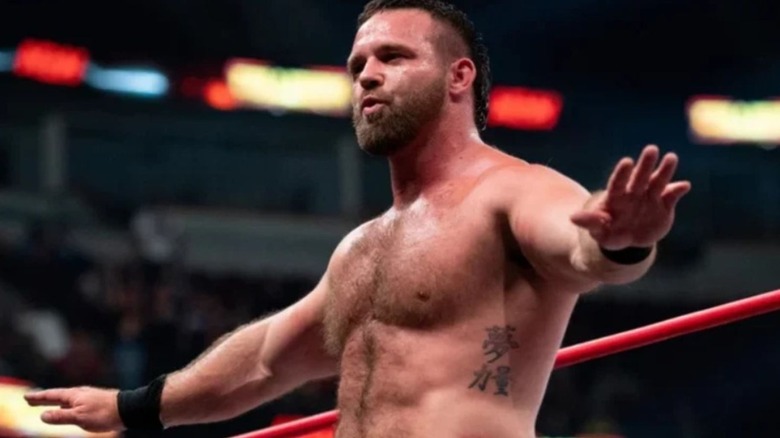 AEW star and one-half of FTR, Cash Wheeler, stands on the ring apron and poses for the crowd before a match.