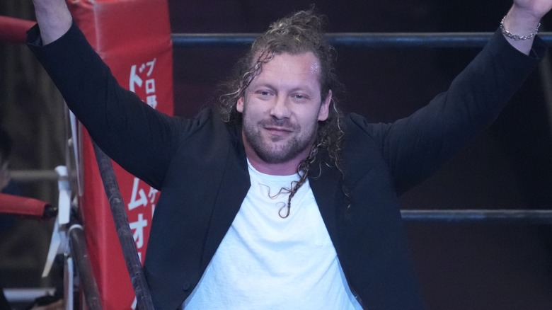 Kenny Omega with his arms in the air