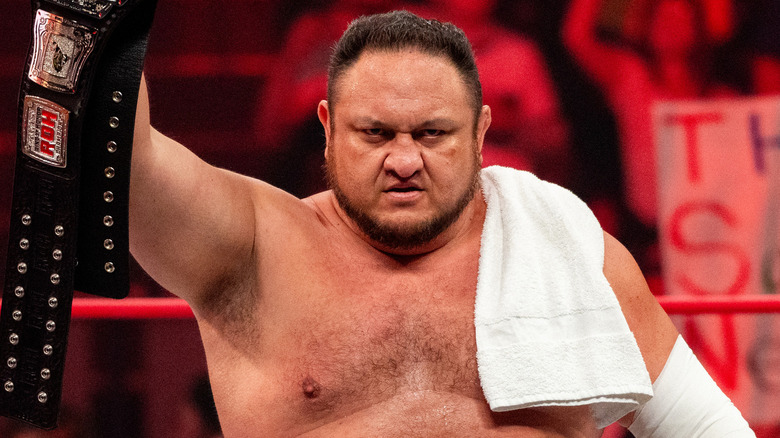 Samoa Joe holding up his title belt