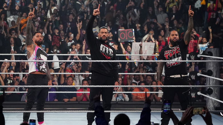 Jey Uso, Roman Reigns, and Jimmy Uso each holding up a finger