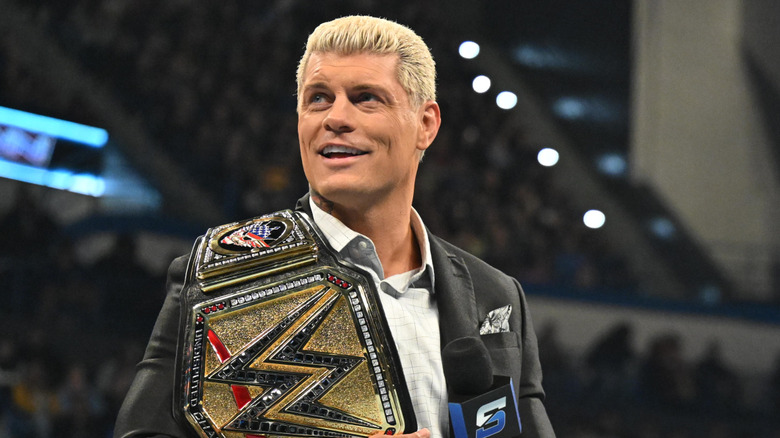 Cody Rhodes in a suit, with his title