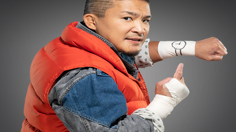 Kushida looks over his shoulder and points to a cartoon watch drawn on his bandaged wrist.