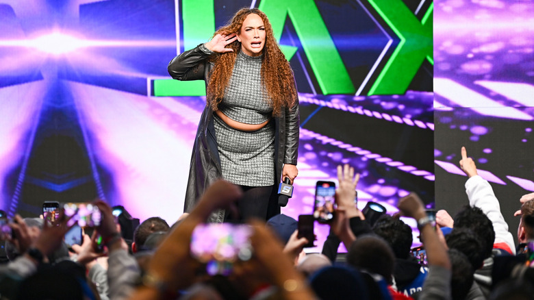 Nia Jax holds a hand to her ear during her entrance at WWE Royal Rumble