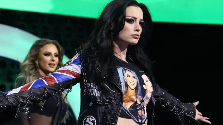 Saraya stands on the stage, hands outstretched