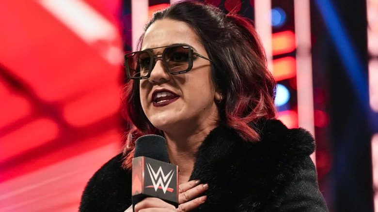Bayley wearing sunglasses and talking into a microphone