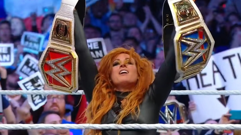 Becky Lynch holding up both titles