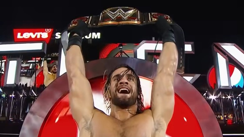 Seth Rollins holding the championship above his head
