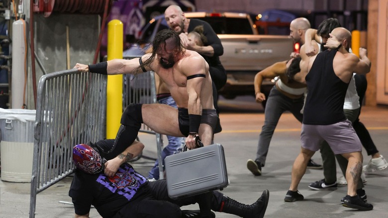 PAC kicks Evil Uno's face in in the forefront. In the background, Jon Moxley, Claudio Castagnoli, and Wheeler Yuta lock up with three other men.