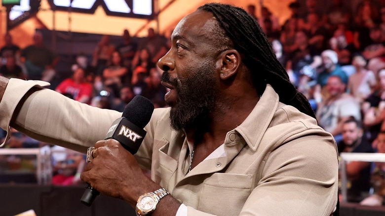 Booker T holding a mic near the WWE NXT commentary table