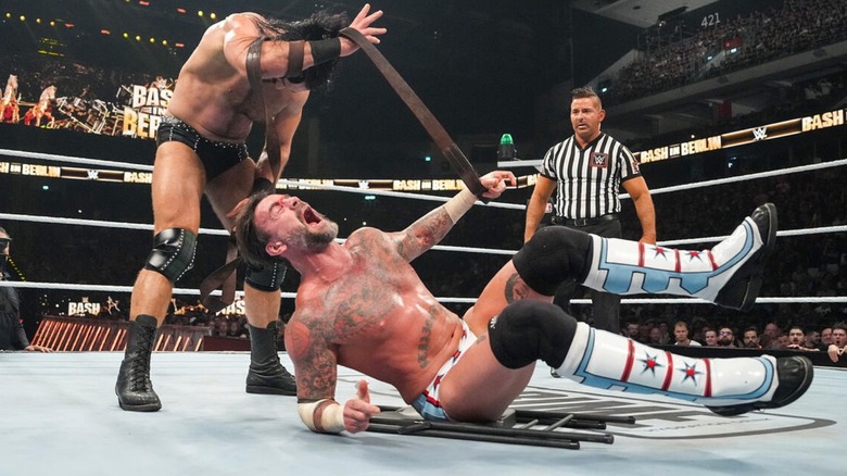 Drew McIntyre looks down at CM Punk, writhing in pain, during their strap match at Bash in Berlin.