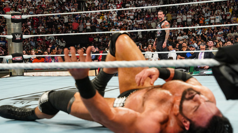 CM Punk looks over a fallen Drew McIntyre