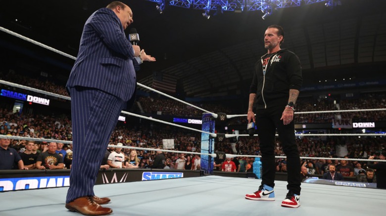 CM Punk and Paul Heyman with a microphone in the ring