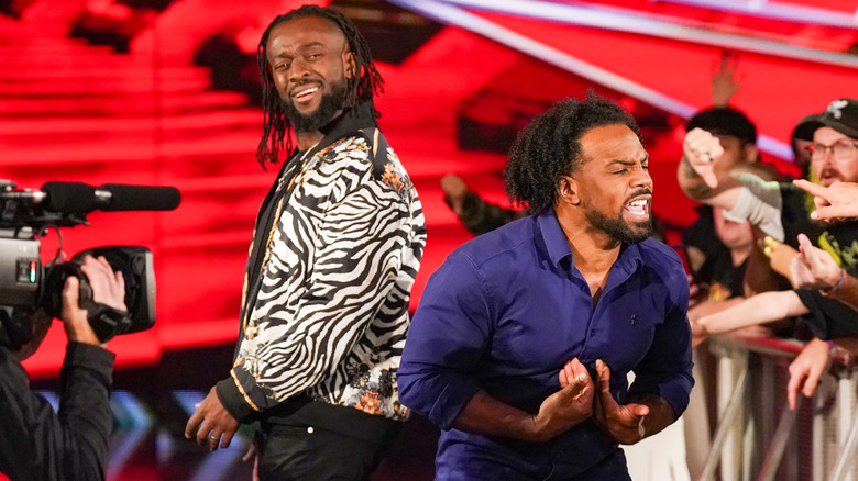 Kofi Kingston looking confused, while Xavier Woods yells at a fan