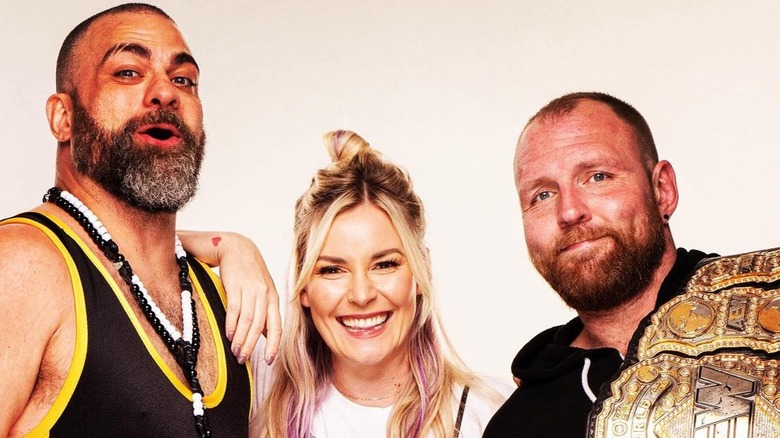 Eddie Kingston, Renee Paquette, and Jon Moxley pose together during a studio shot