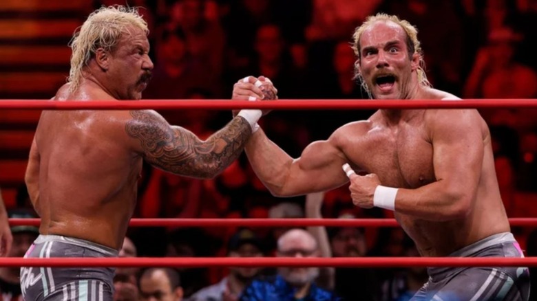 The Outrunners grasp hands in the middle of the ring and pose during a match on AEW television.