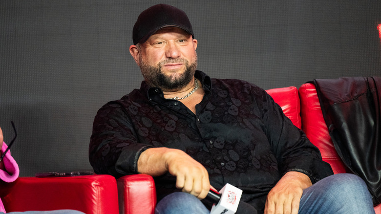 Bully Ray holding a mic and sitting on a red couch