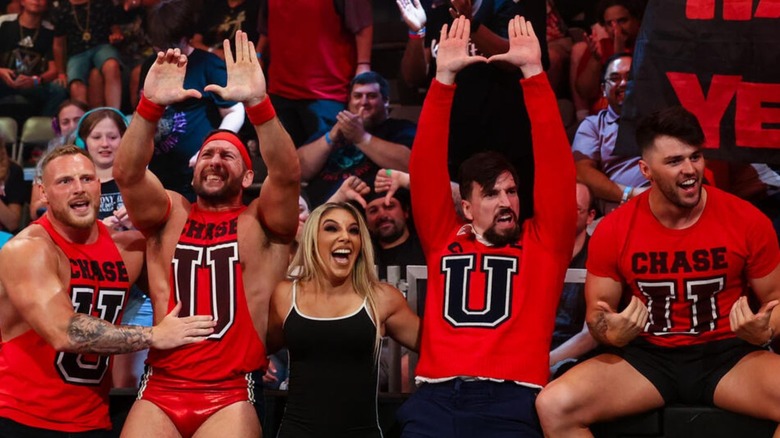 Ridge Holland, Duke Hudson, Thea Hail, Andre Chase, and Riley Osbourne celebrate near the WWE fans by the ring barricade following a win on a "WWE NXT" premium live event.