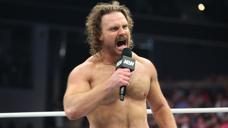 A shirtless "Hangman" Adam Page shouts into the microphone.