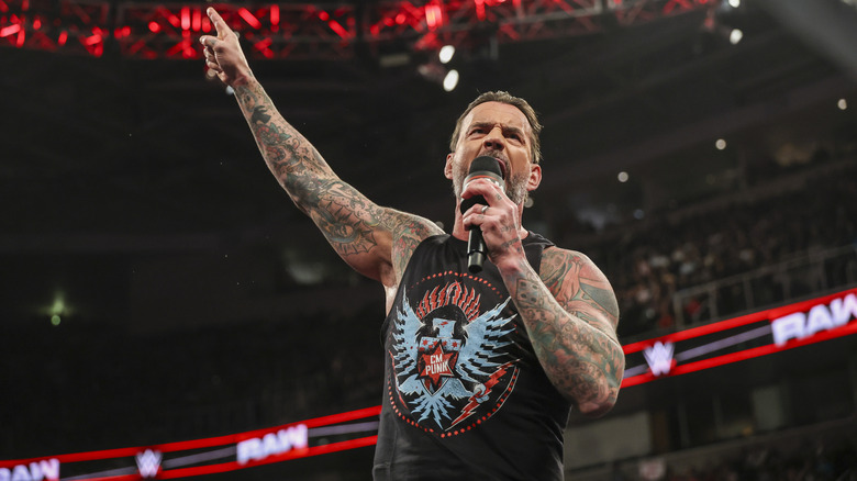 CM Punk holding a microphone pointing upwards on WWE Raw