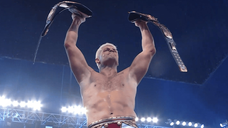 Cody Rhodes holds up the WWE Universal Championship and the Winged Eagle title.