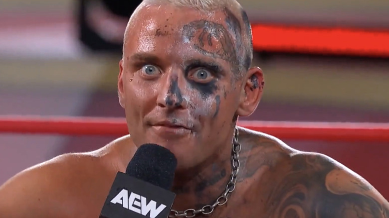 Darby Allin leans over the top rope with a microphone