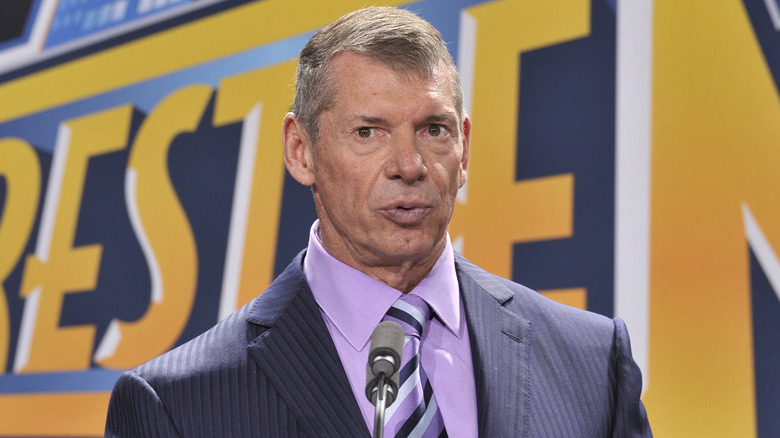 Vince McMahon standing in front of a WWE WrestleMania background