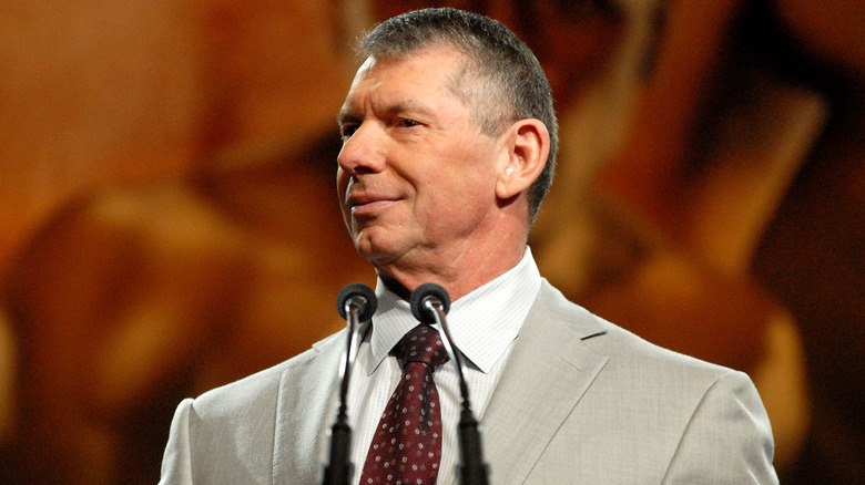 Vince McMahon standing in front of microphones