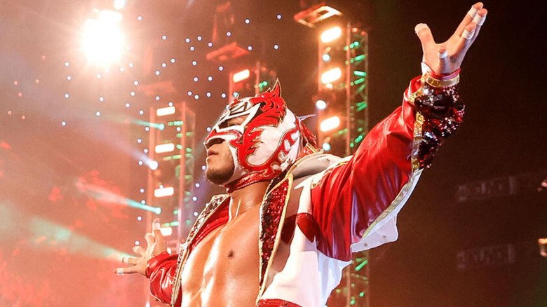 Dragon Lee raises his arms as a stadium lights up in red and green for his entrance.